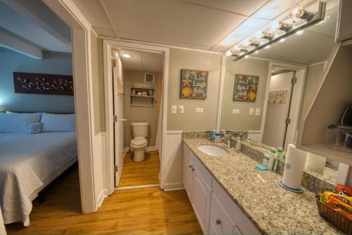 a bathroom with a sink and a toilet and a bed at Waterway View Studio 2 w/ Pool, 1 mile to Wrightsville Beach in Wilmington