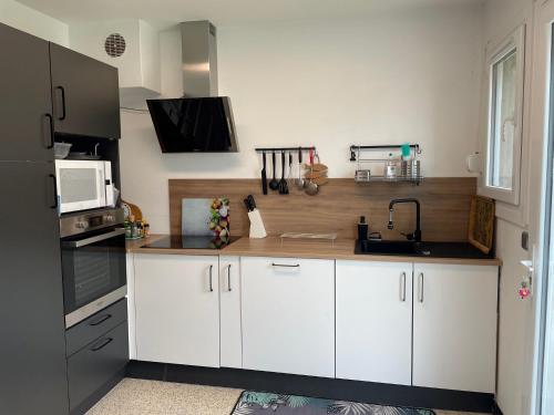 une cuisine avec des armoires blanches et un réfrigérateur noir dans l'établissement Du gite dans les Toiles, à Wimereux