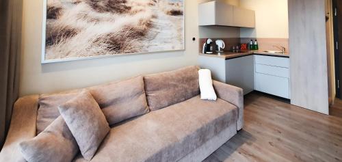 un sofá marrón en una sala de estar con cocina en Holiday Home Bel Mare 307e, en Międzyzdroje
