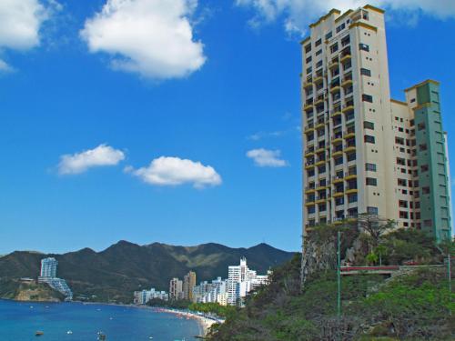 un edificio alto en una colina junto a una playa en Apartamentos El Peñon - Frente al Mar by SOHO, en Santa Marta