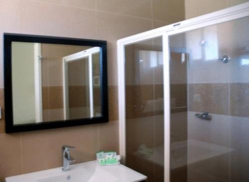 bagno con doccia, lavandino e specchio di Tocumwal Golf Resort a Tocumwal