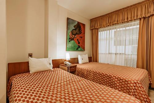 a hotel room with two beds and a window at Hotel Casa de la Luna in Chiclayo
