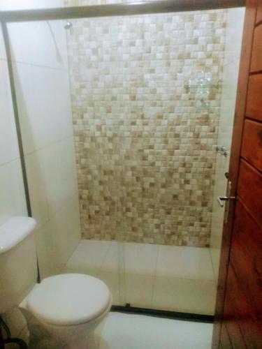 a bathroom with a shower with a toilet and a glass door at Pousada Sitio do Visconde in Visconde De Maua