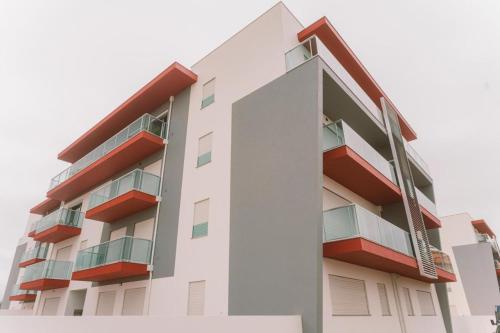 ein weißes Apartmenthaus mit roten Balkonen in der Unterkunft Consolação Beach Apartment in Peniche