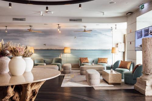 a lobby with a table and chairs and a painting of the ocean at Corpo Santo Lisbon Historical Hotel in Lisbon