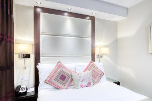 a bedroom with a white bed with two pillows at Grand Royale Hyde Park in London