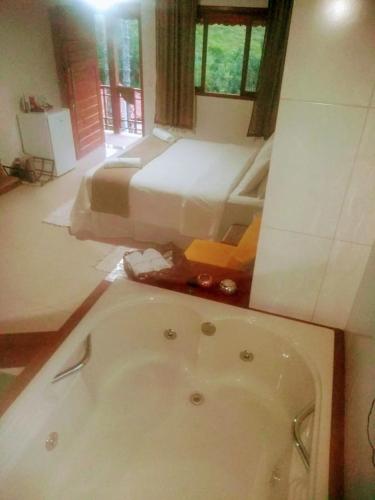 a bathroom with a bath tub and a bed at Pousada Sitio do Visconde in Visconde De Maua
