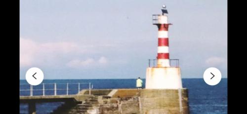 a lighthouse next to the ocean with two arrows at Amble Holiday Home in Amble