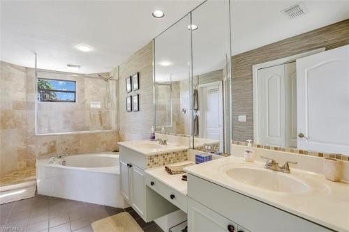 a bathroom with two sinks and a tub and a large mirror at SUPERB LAKESIDE VILLA WITH PRIVATE POOL NAPLES in Naples