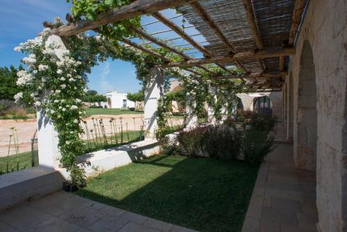 an outdoor pergola with white flowers on it at Masseria Santo Scalone in Ostuni