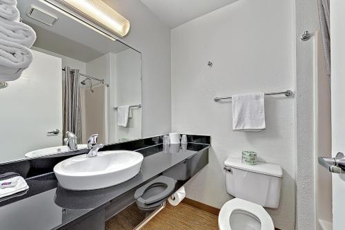 
a bathroom with a toilet, sink, and mirror at Motel 6-Glenview, IL - Chicago North in Glenview
