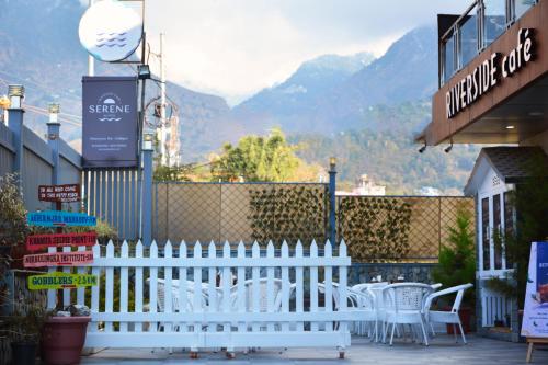 a white fence with white chairs and mountains in the background at SERENE SUITES in Dharamshala