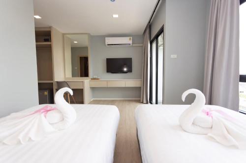 two swans are sitting on two beds in a room at Napa Hotel Ratchaburi in Ratchaburi