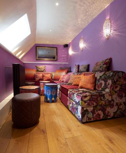 a living room with purple walls and a couch at The Dog and Badger in Marlow