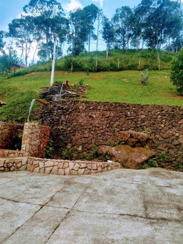 a stone wall with a fountain in a field at Pousada Sitio do Visconde in Visconde De Maua