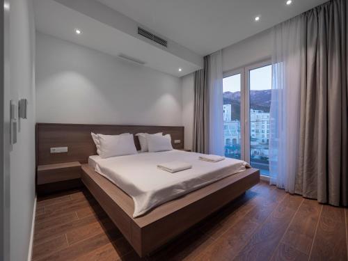 a bedroom with a large bed and a large window at Horizon Two bedroom Penthouse with Hot tub in Becici