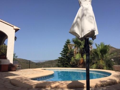 an umbrella standing next to a swimming pool at One Bed Apartment overlooking Jalon Valley, Costa Blanca in Alcalalí