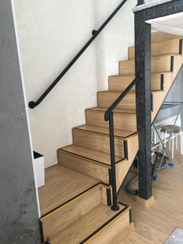 escalera con escaleras de madera y barandilla negra en Современные и уютные аппартаменты en Borovoye