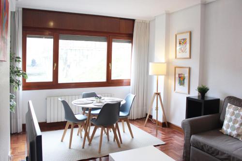 ein Wohnzimmer mit einem Tisch, Stühlen und einem Sofa in der Unterkunft Bilbao Apartment Lasai con parking directo in Bilbao