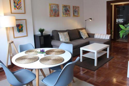 Bilbao Apartment Lasai con parking directo في بلباو: غرفة معيشة مع أريكة وطاولة وكراسي