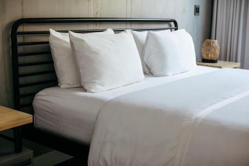a bed with a white comforter and pillows at Mother Earth Vegan Hotel in Tamarindo