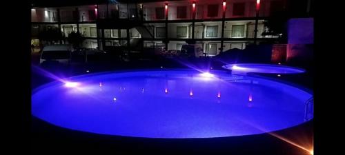 una gran piscina con luces azules frente a un edificio en Hotel Flamingo Irapuato, en Irapuato