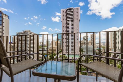 a balcony with chairs and a table and a view of buildings at Ohia Waikiki Studio Suites in Honolulu