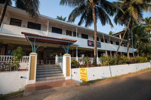 a building with stairs and palm trees in front of it at The Woodside Inn in Benaulim