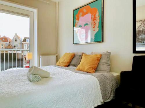 1 dormitorio con 1 cama blanca grande con almohadas de color naranja en Best Location in Centrum, en Leiden