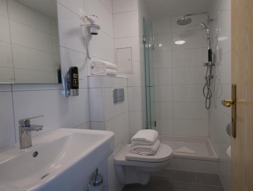 a bathroom with a toilet and a sink and a shower at Hotel Merian in Cologne