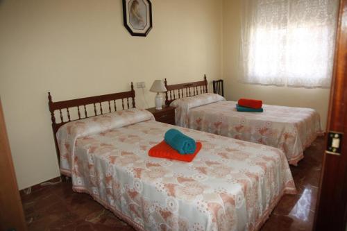 two beds in a room with red and blue pillows at VUT Flor de Romero in Los Yébenes