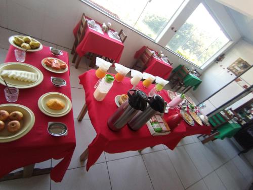 a red table with breakfast foods and drinks on it at Pousada Da Santina in Visconde De Maua