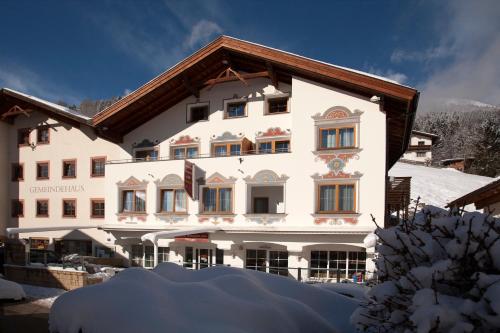 Un grand bâtiment blanc avec de la neige devant lui dans l'établissement Die Reblaus, à Ladis