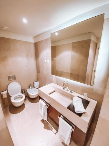 a bathroom with a sink and a toilet and a mirror at Troia - Paraíso a um passo de Lisboa in Troia