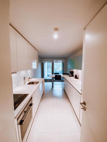 a kitchen with white cabinets and a table in it at Troia - Paraíso a um passo de Lisboa in Troia