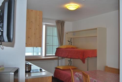 a small room with two bunk beds and a desk at Hotel Garni Arnica in Molveno