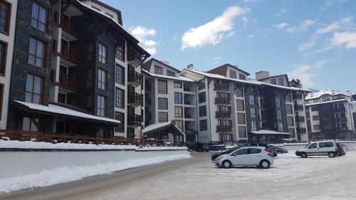 Belvedere luxury apartment في بانسكو: سيارتين متوقفتين في موقف للسيارات أمام المباني