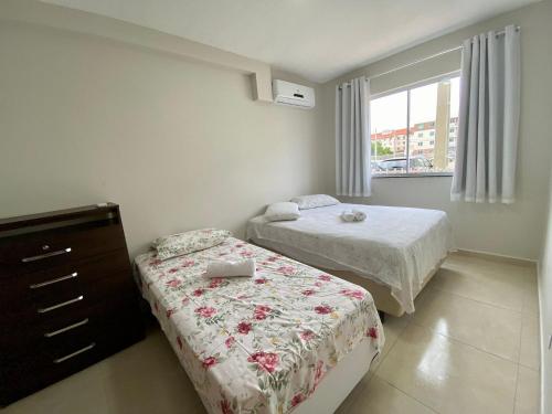 a bedroom with two beds and a dresser and a window at Vento do Mar - Em frente à PRAIA dos Milionários in Ilhéus