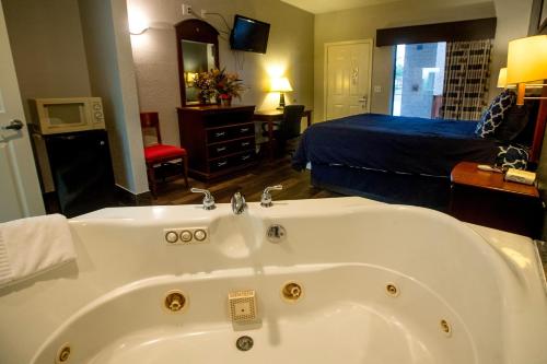 1 dormitorio con 1 cama y baño con bañera. en Magnolia Inn and Suites, en Magnolia