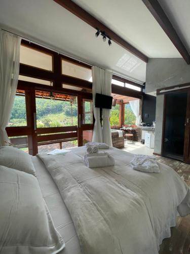 ein großes weißes Bett in einem Zimmer mit großen Fenstern in der Unterkunft I'Lumiar Loft in Lumiar