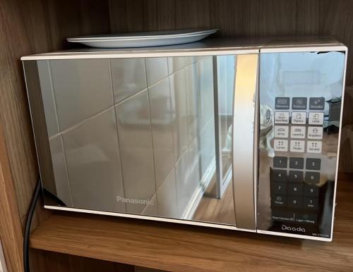 a microwave sitting on a shelf with a remote control at Hotel Brás in Sao Paulo