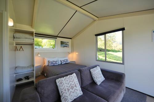 a tiny house with a couch and a bed at Akaroa Top 10 Holiday Park in Akaroa
