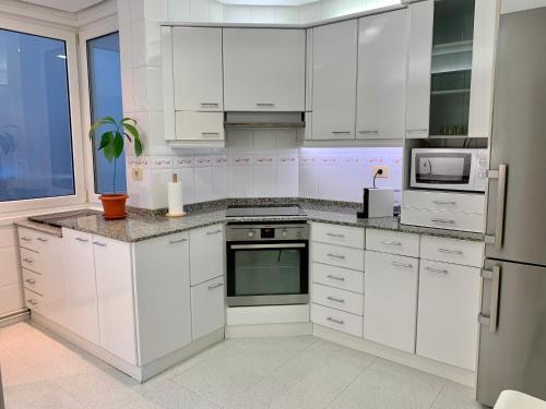 una cocina blanca con armarios y electrodomésticos blancos en Habitación privada en Bilbao Centro, en Bilbao