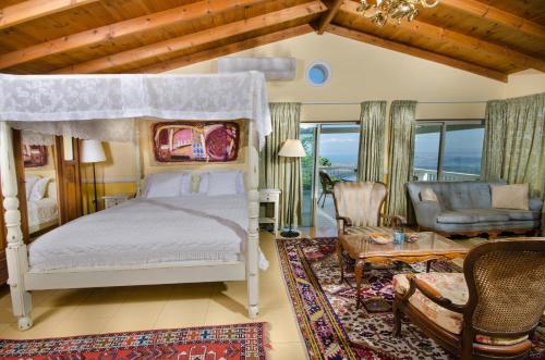 a bedroom with a canopy bed and a living room at Ha'Seuda Ha'Achrona Suites in Amirim