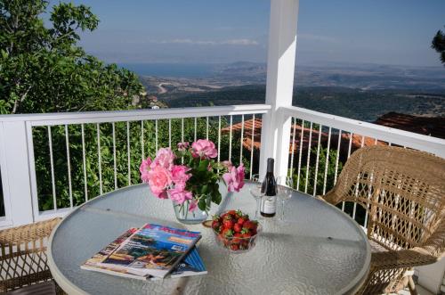 a table with flowers and a bottle of wine on a balcony at Ha'Seuda Ha'Achrona Suites in Amirim