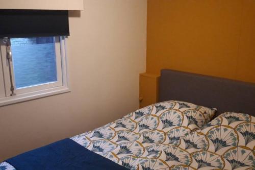 een slaapkamer met een bed en een raam bij Chalet op mooie rustige plek in Enschede