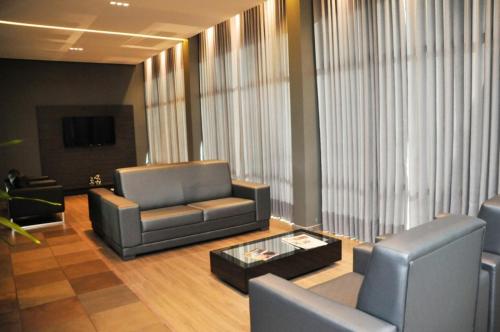 a lobby with two chairs and a couch and a table at Hotel Vivendas Centro in Erechim