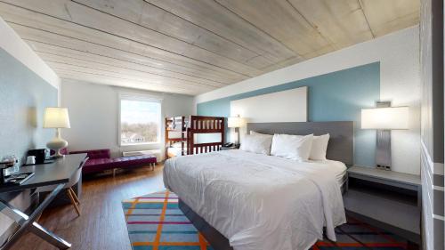 a bedroom with a large white bed and a desk at voco College Station Aggieland by IHG in College Station