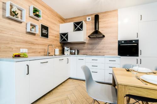 cocina con armarios blancos y pared de madera en Apartament Rezydencja Vintage No2, en Olsztyn