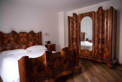 ein Schlafzimmer mit einem Holzbett und einem großen Spiegel in der Unterkunft B&B LE AQUANE in Ono San Pietro
